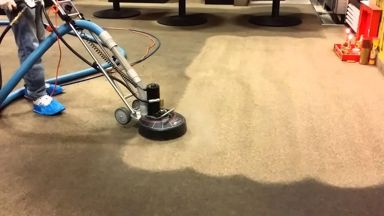 A heavily soiled carpet mid-clean, the cleaned strip running beside untouched pile