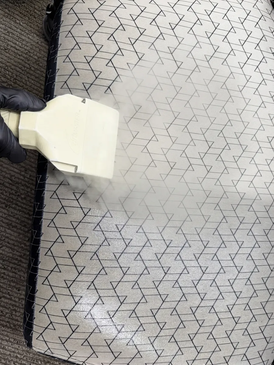 An ApexClean technician steam-cleaning a mattress with a hot-water extraction hand tool in a Sunnyvale, Auckland home